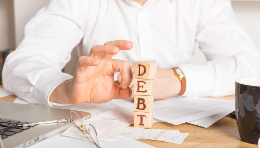 Businessman removes wooden blocks with the word Debt. Reduction or restructuring of tax. Bankruptcy announcement. Refusal to pay loans and invalidate them.